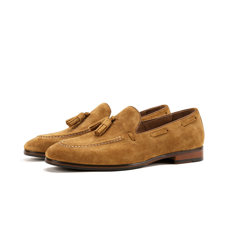 Pair of tan suede loafers with tassels on a white background