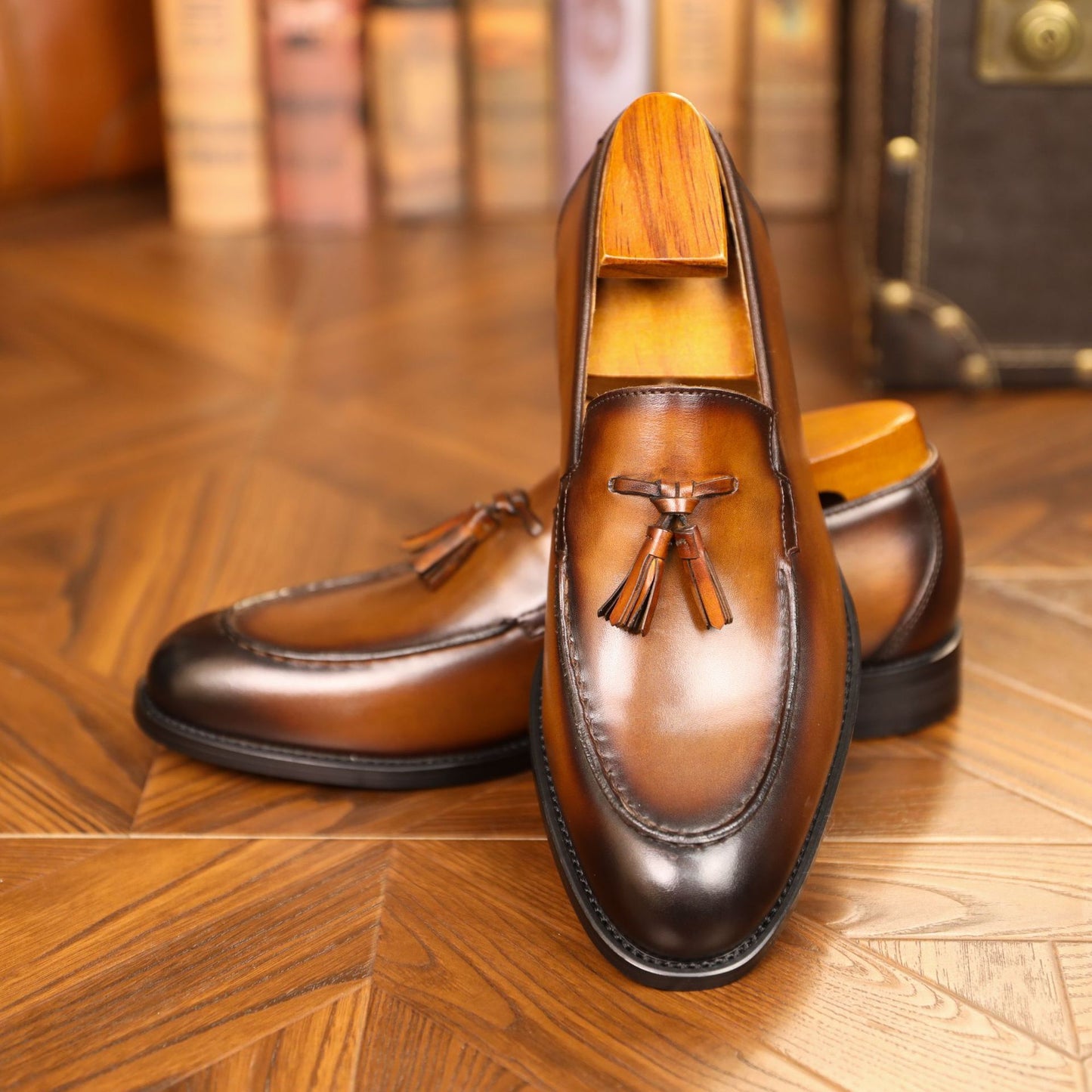 Brown leather loafers with tassels on a wooden floor