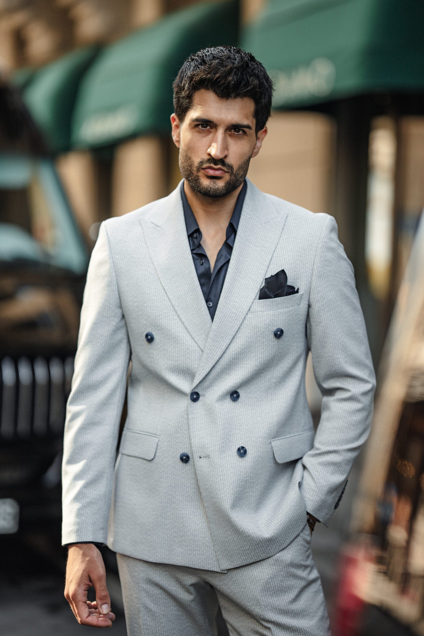 Man wearing a light gray suit with black buttons in an urban setting