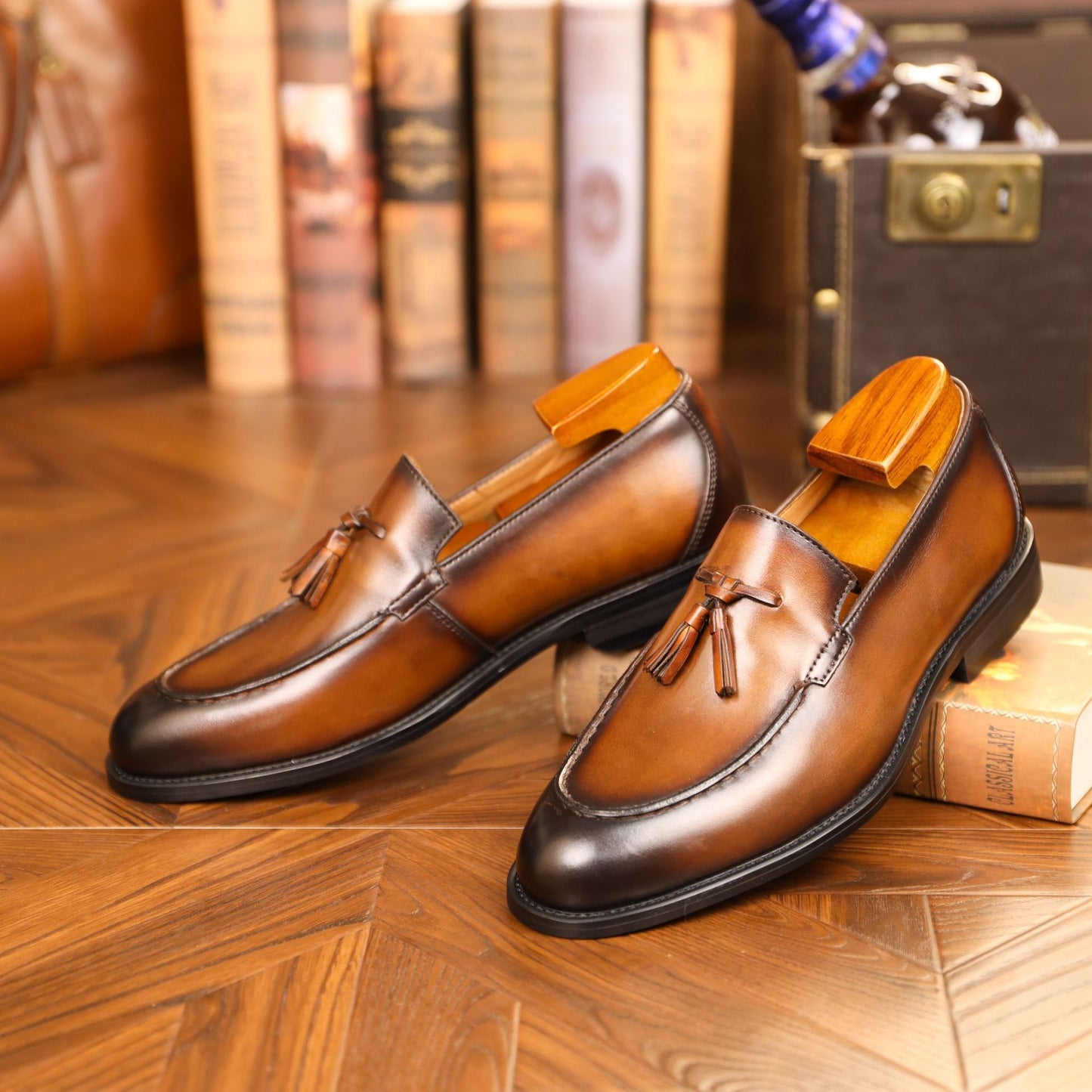 Pair of brown leather loafers with wooden soles on a wooden floor.