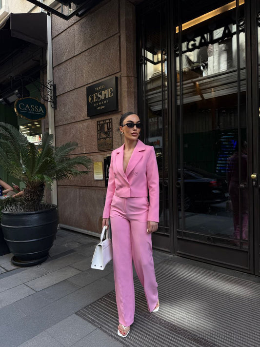 Woman in a pink suit walking on a city street.