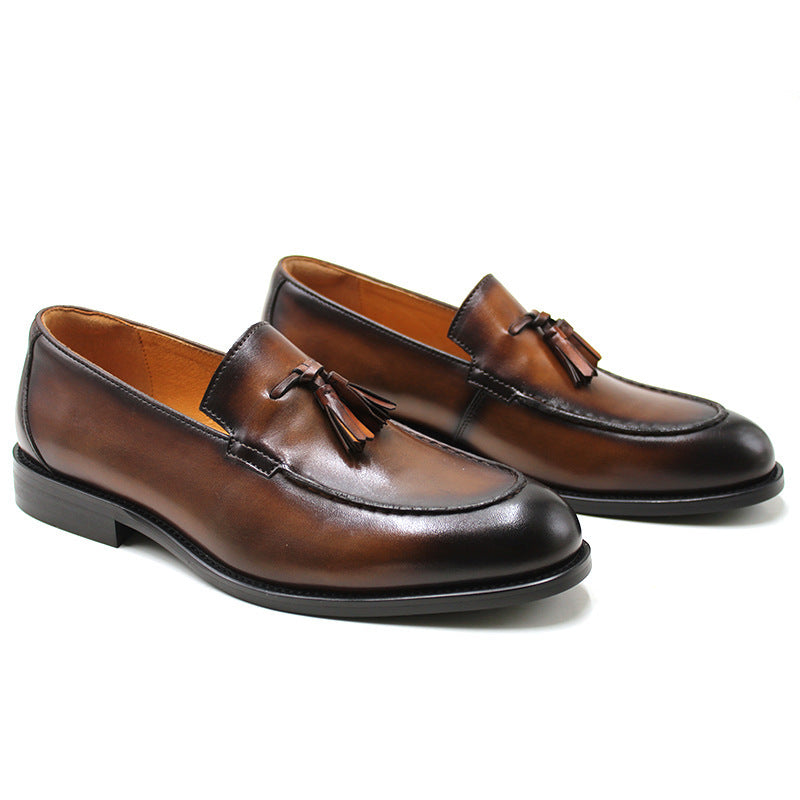 Pair of brown leather loafers with tassels on a white background