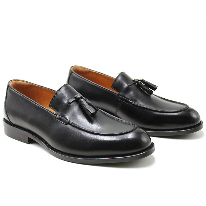 Pair of black leather loafers with tassels on a white background